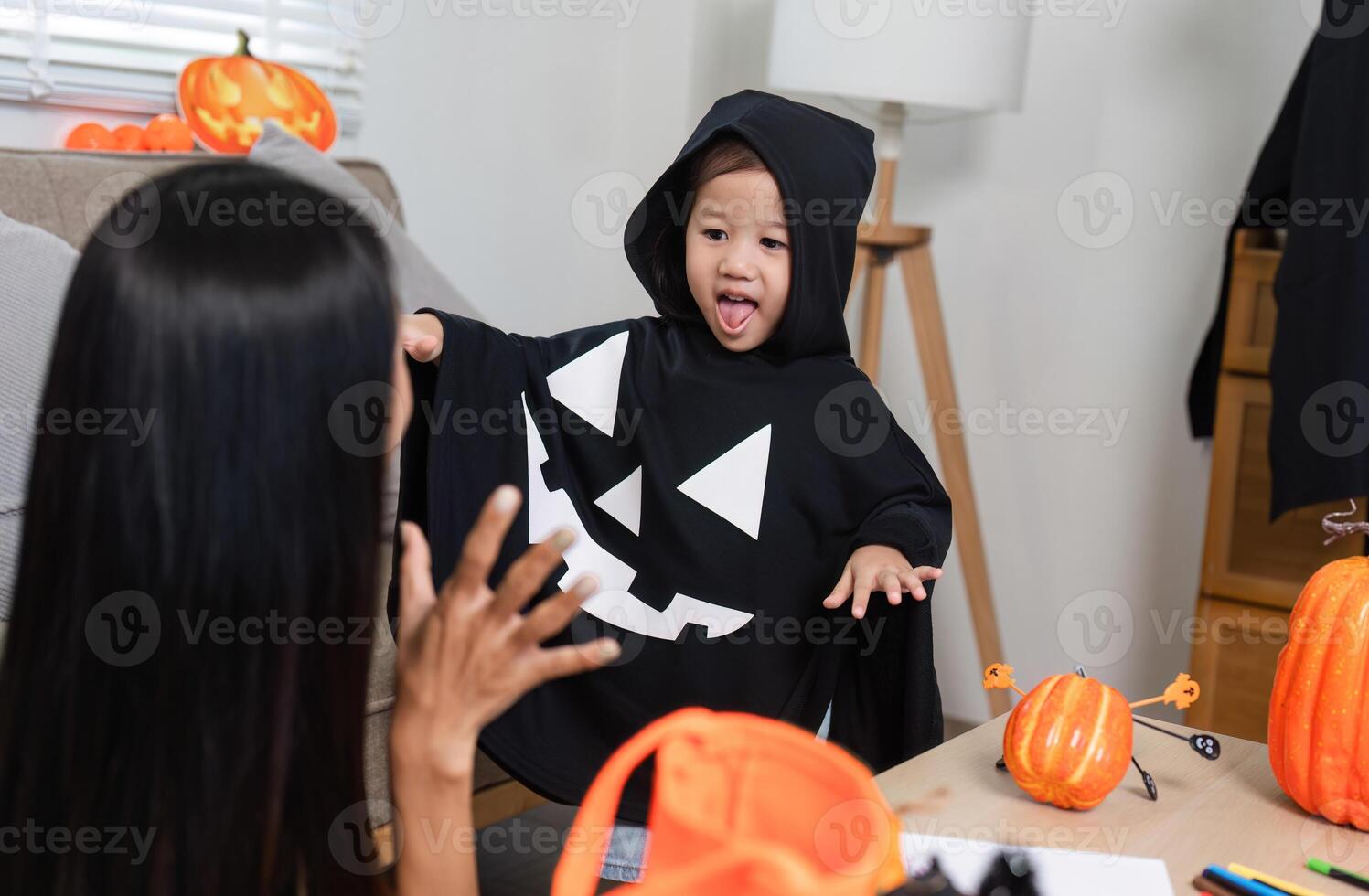 Mother and Daughter Decorating Living Room for Halloween with Pumpkins and Costumes, Creating Festive and Fun Atmosphere photo