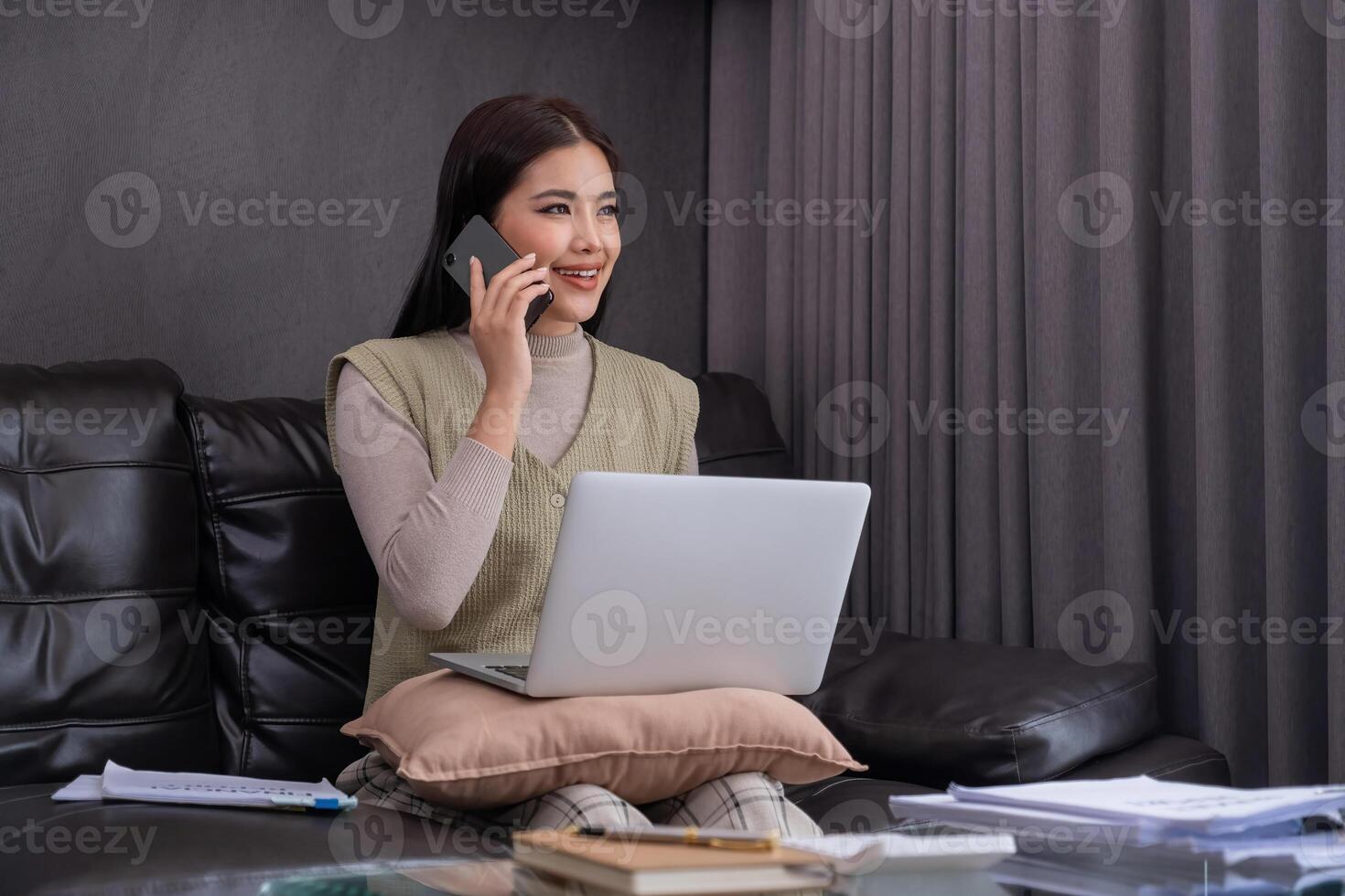 Woman Using Laptop and Smartphone on Sofa. Concept of multitasking and modern lifestyle. photo