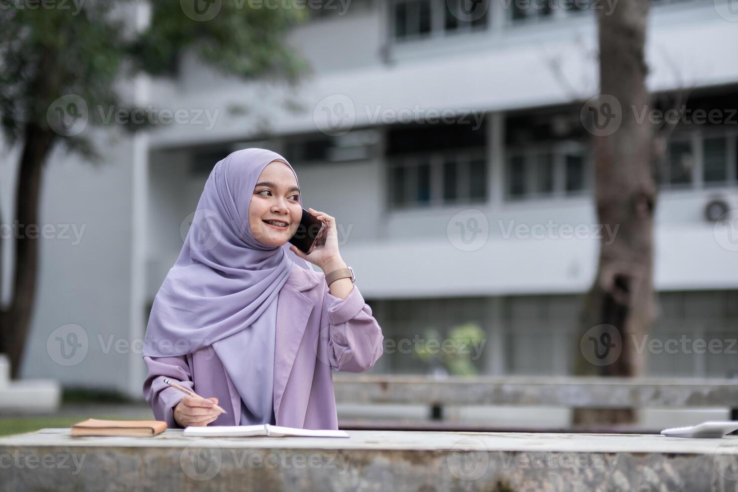 Confident Muslim Girl Student in Hijab Using Smartphone and Studying Outdoors at University Campus photo