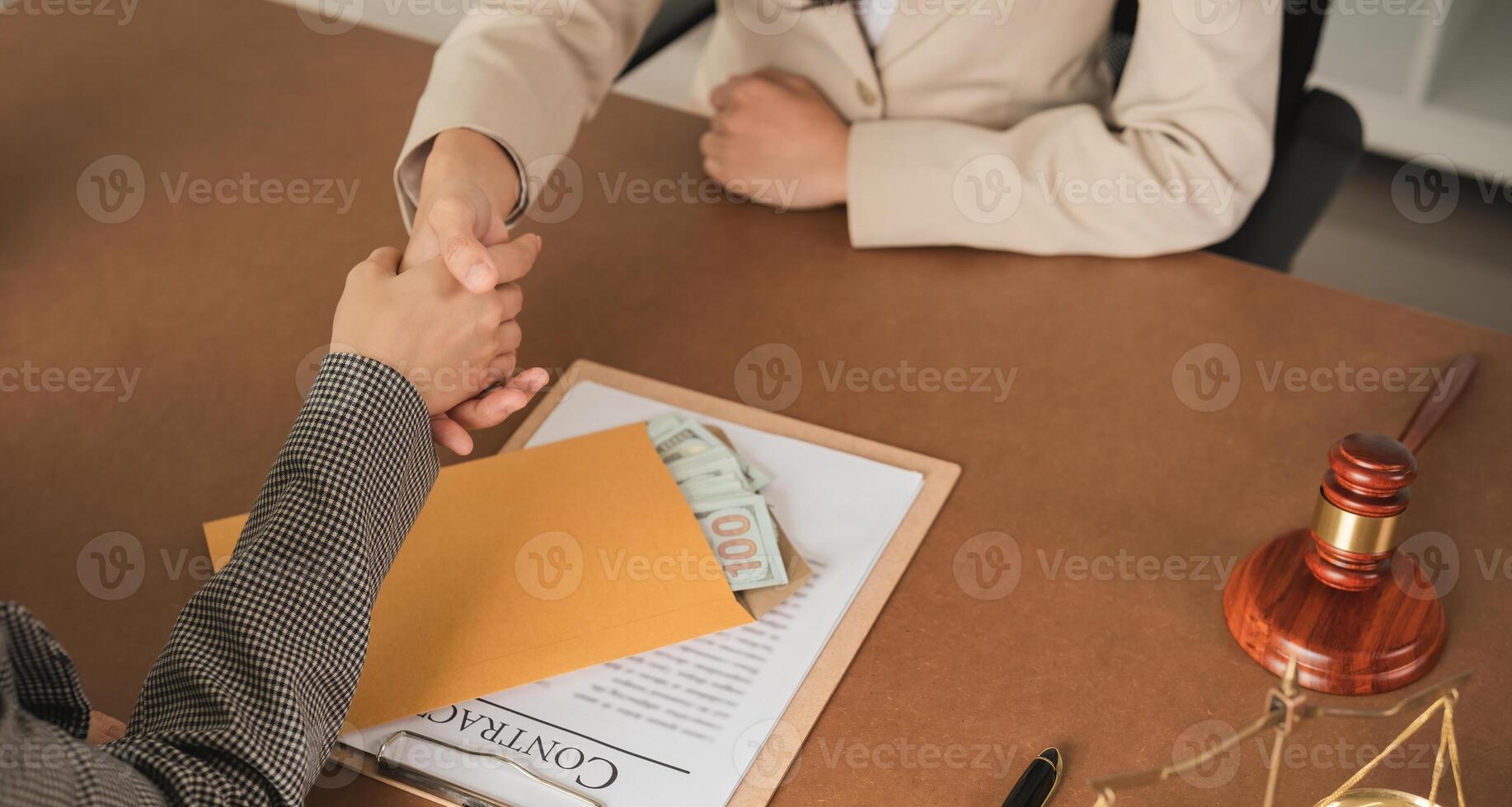 Close-up of business handshake with money in envelope on desk. Concept of business agreement and financial transaction photo