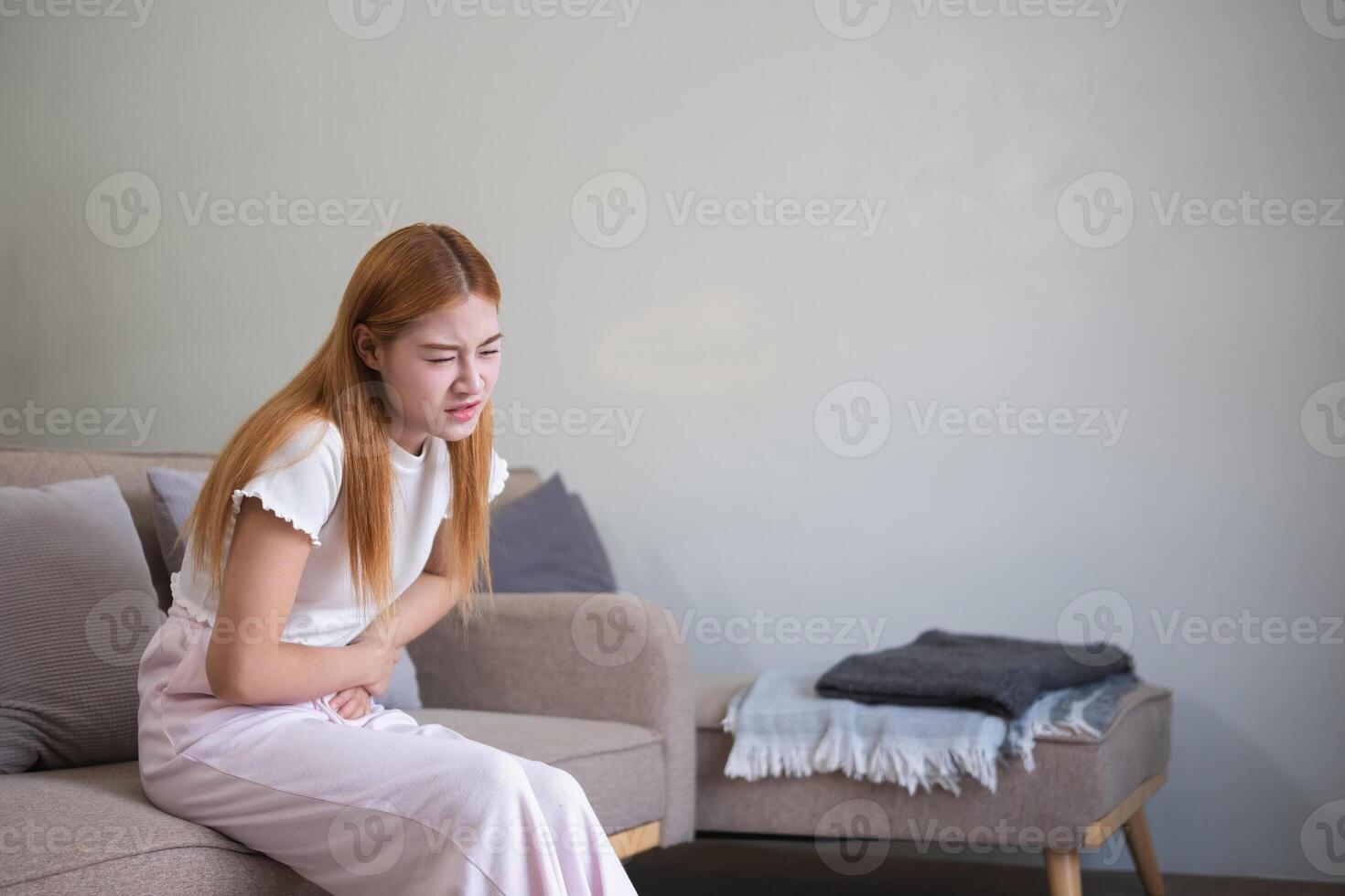 A young Asian woman with abdominal pain from diarrhea or menstrual cramps felt sick and touched her stomach with an unhappy expression. photo