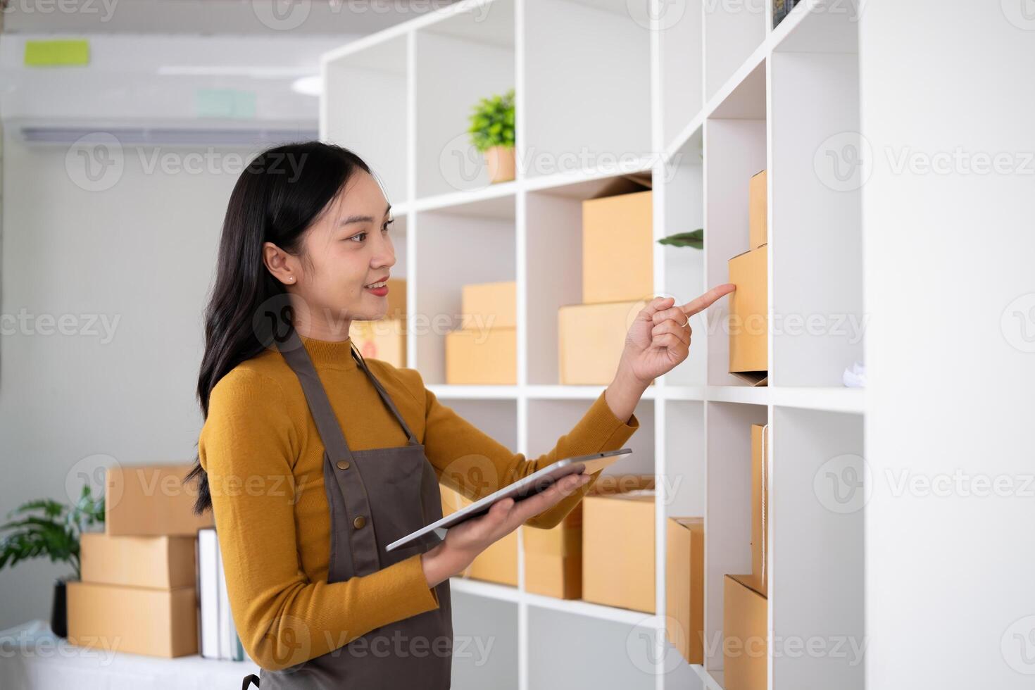 Young woman working in warehouse with packages using tablet for inventory management photo