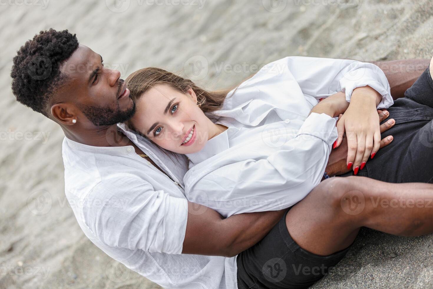 A couple embraces on a sandy beach, enjoying a sunny day while relaxing by the shore during the afternoon photo