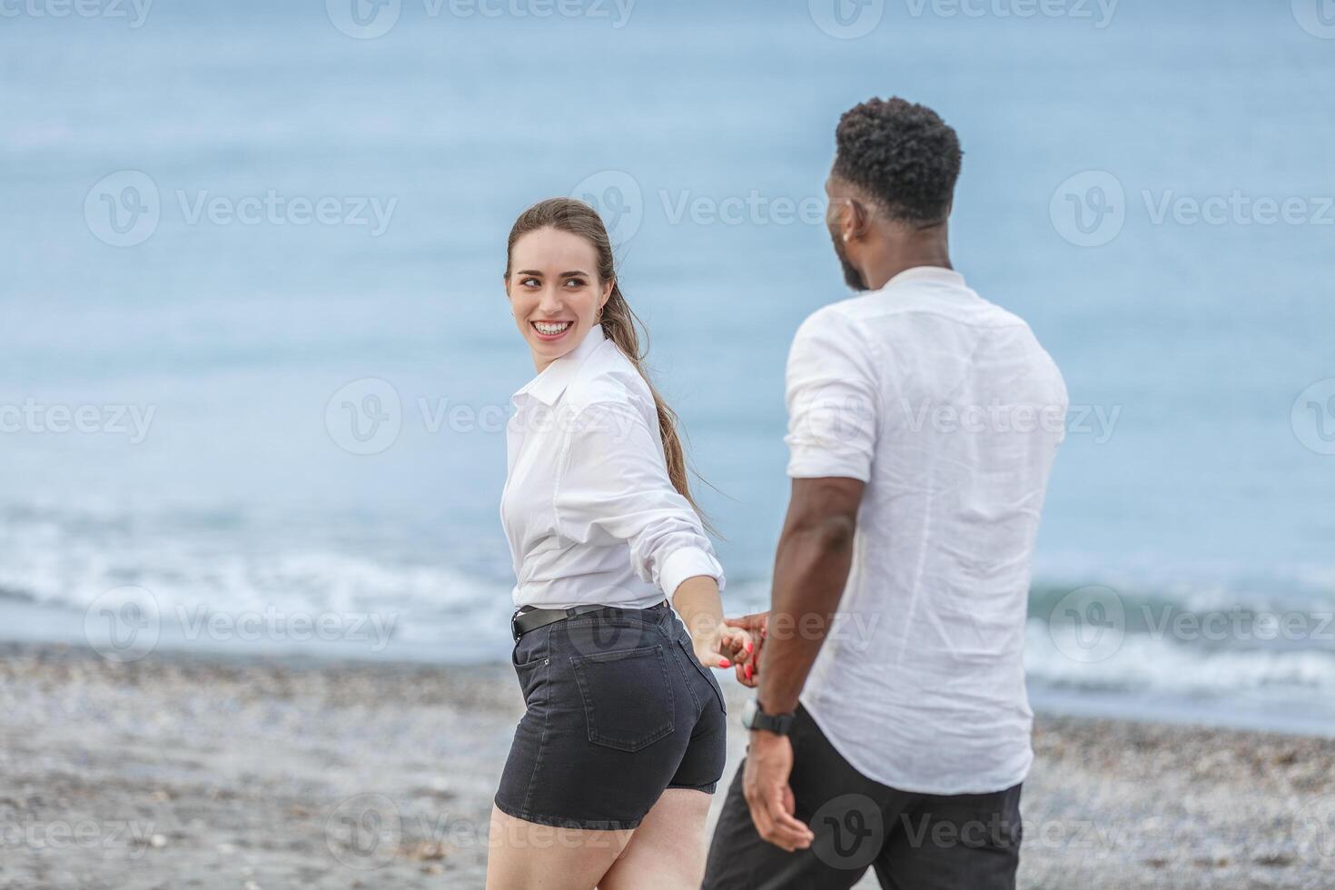 Couple walking hand in hand along the beach at Playa del Zapillo in Almeria, Spain during a sunny day photo