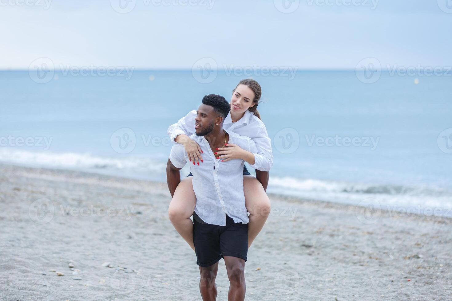 Couple enjoying a playful day at Zapillo Beach in Almeria, Spain, with a romantic piggyback ride under a cloudy sky photo
