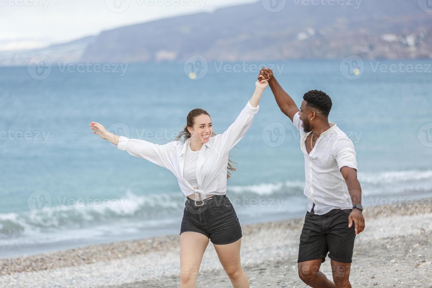 Couple joyfully dancing at Playa del Zapillo beach in Almeria, Spain, enjoying a sunny day by the sea together photo