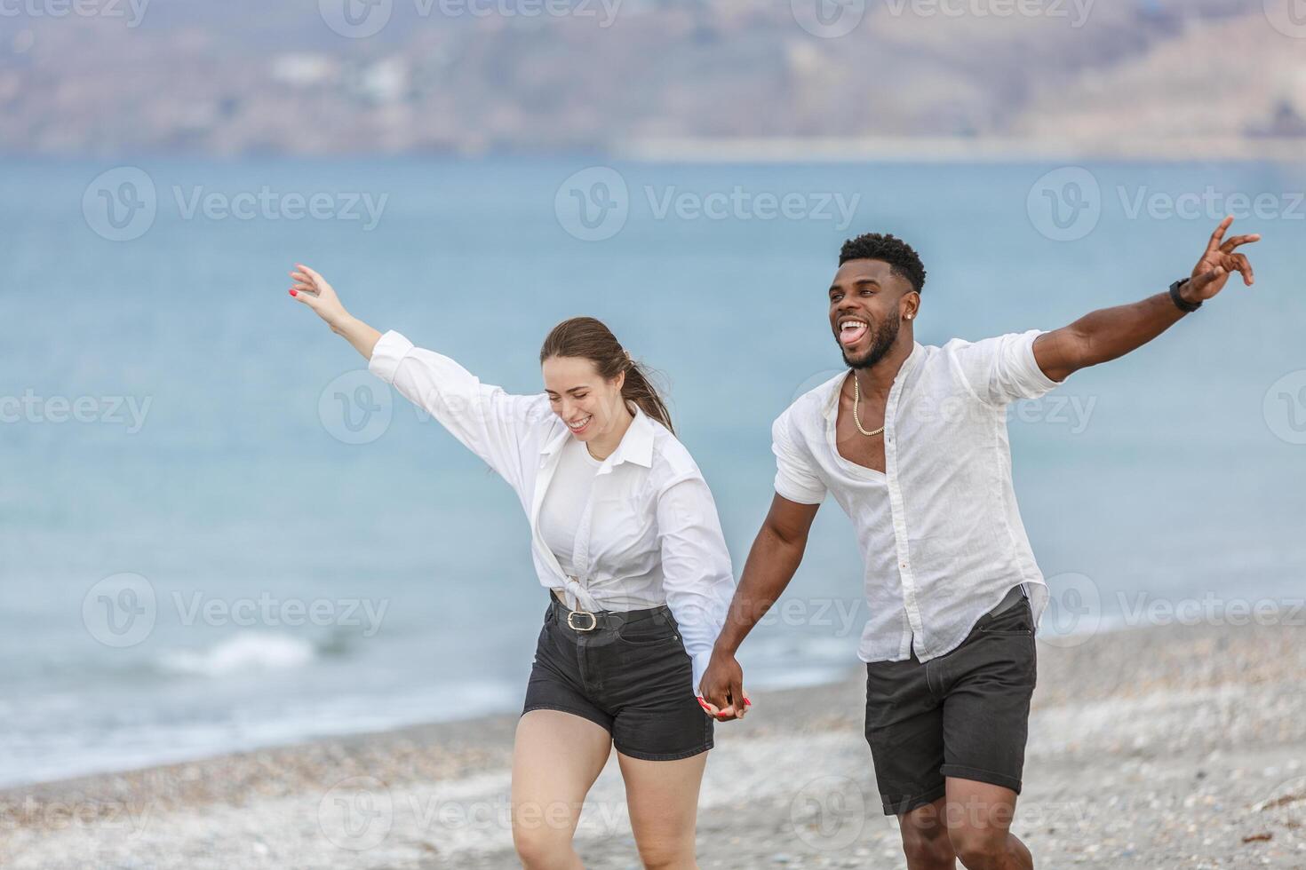 Couple joyfully running along the beach at Playa del Zapillo in Almeria, Spain on a sunny day photo
