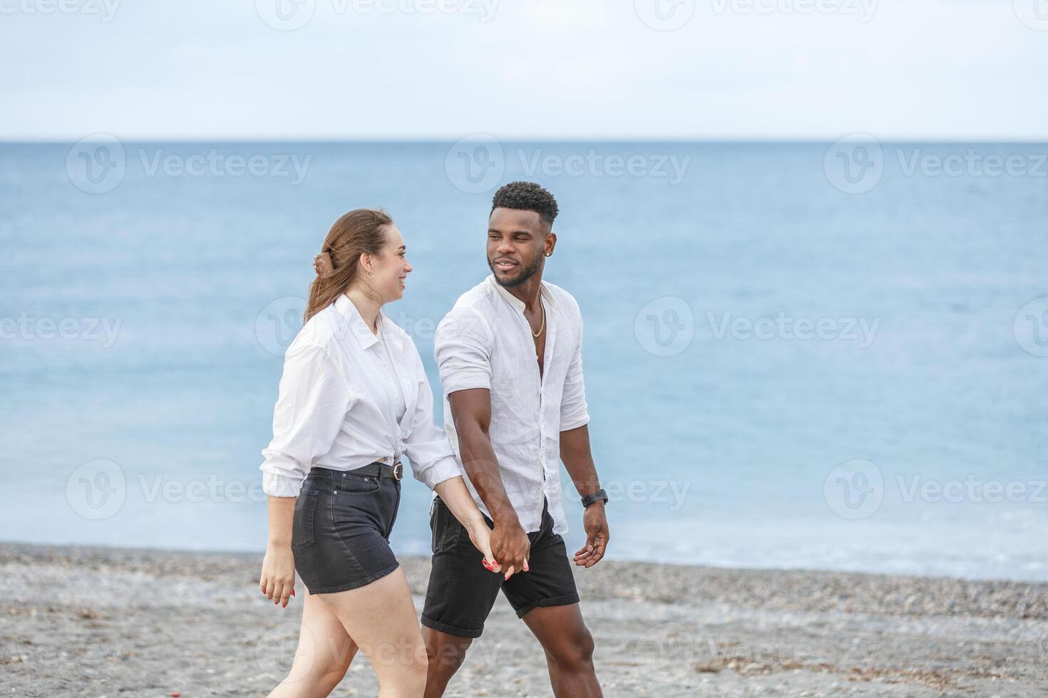 Couple walking hand in hand along the beach at Playa del Zapillo in Almeria, Spain during a sunny day photo