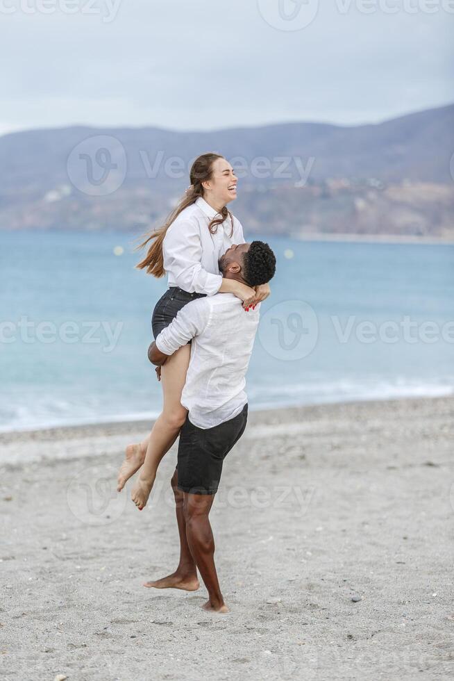 Couple enjoying a playful moment together at Playa del Zapillo beach in Almeria, Spain during a cloudy afternoon photo