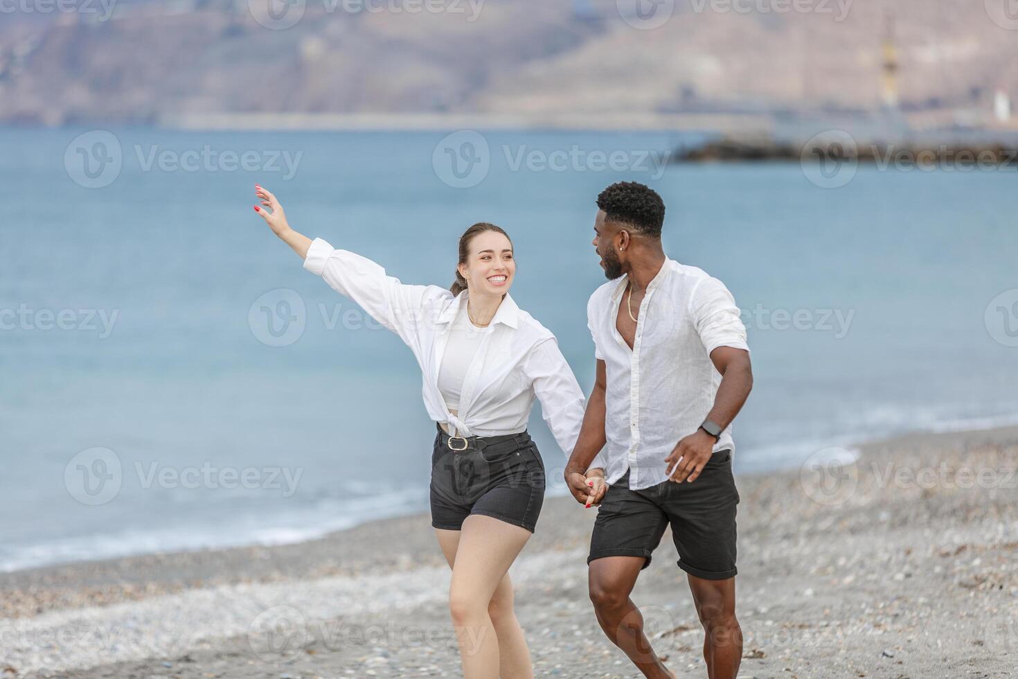 Couple enjoying a joyful moment while walking hand in hand on the shoreline at Playa del Zapillo in Almeria, Spain photo
