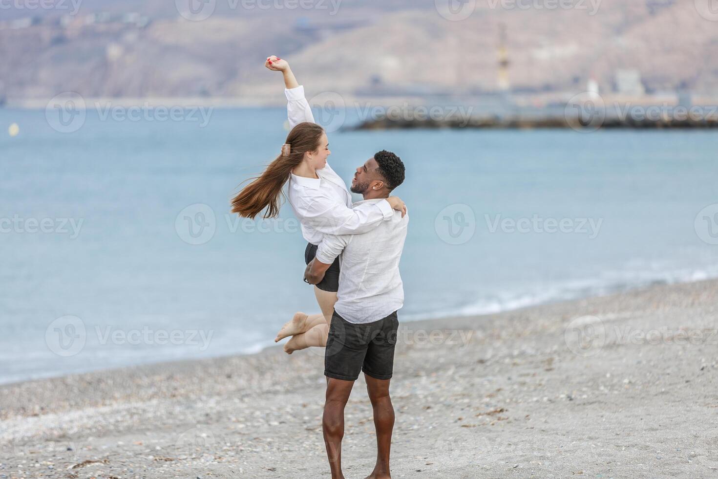 A joyful couple embraces on the beach at Playa del Zapillo, Almeria, enjoying a sunny day and creating lasting memories photo