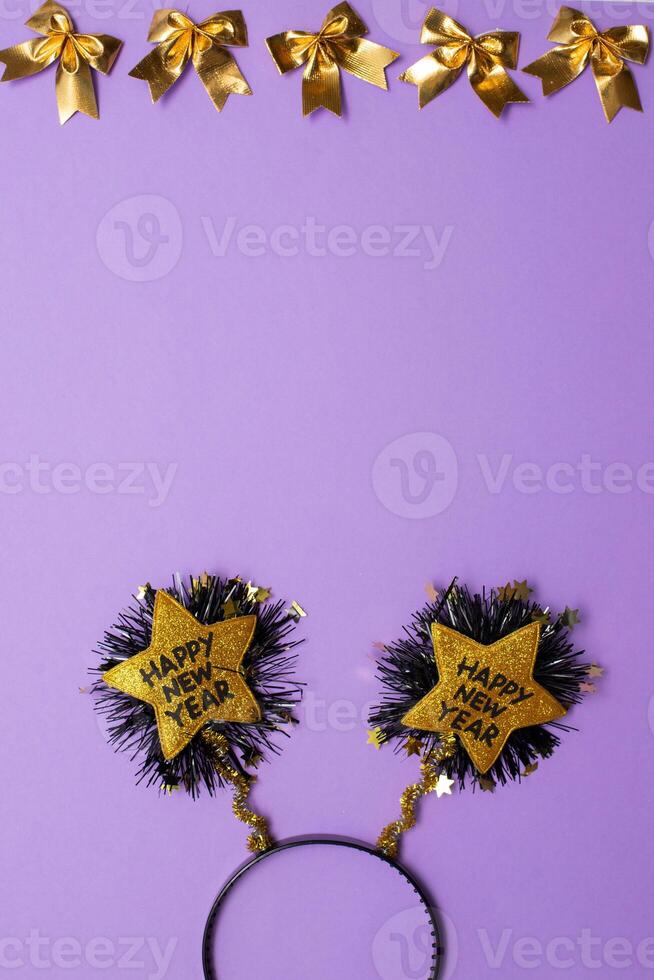 New Year's decor in the form of a golden star shape with black colour text Happy New Year , and christmas decoron purple background.Copy space.Top view photo.Flatlay.Vertical photo. photo