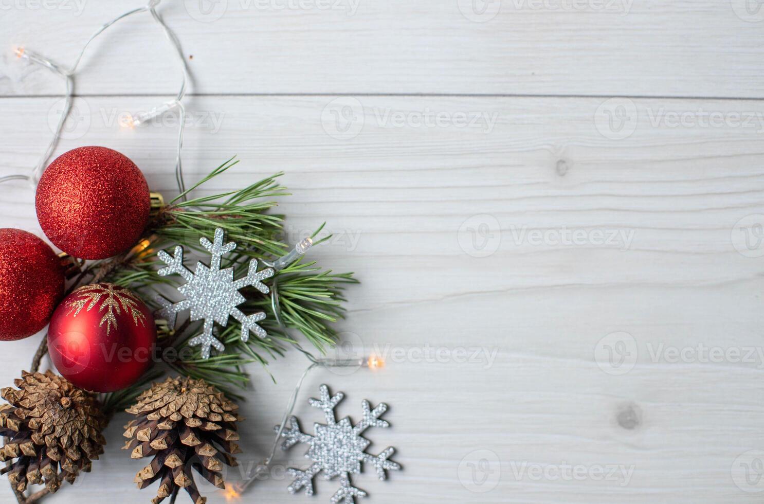 Top view photo christmas tree toys of red colour,pine cones,lights garland,wooden silver snowflakes on grey wooden background for greeting card. Xmas backdrop with space for text.Copyspace.
