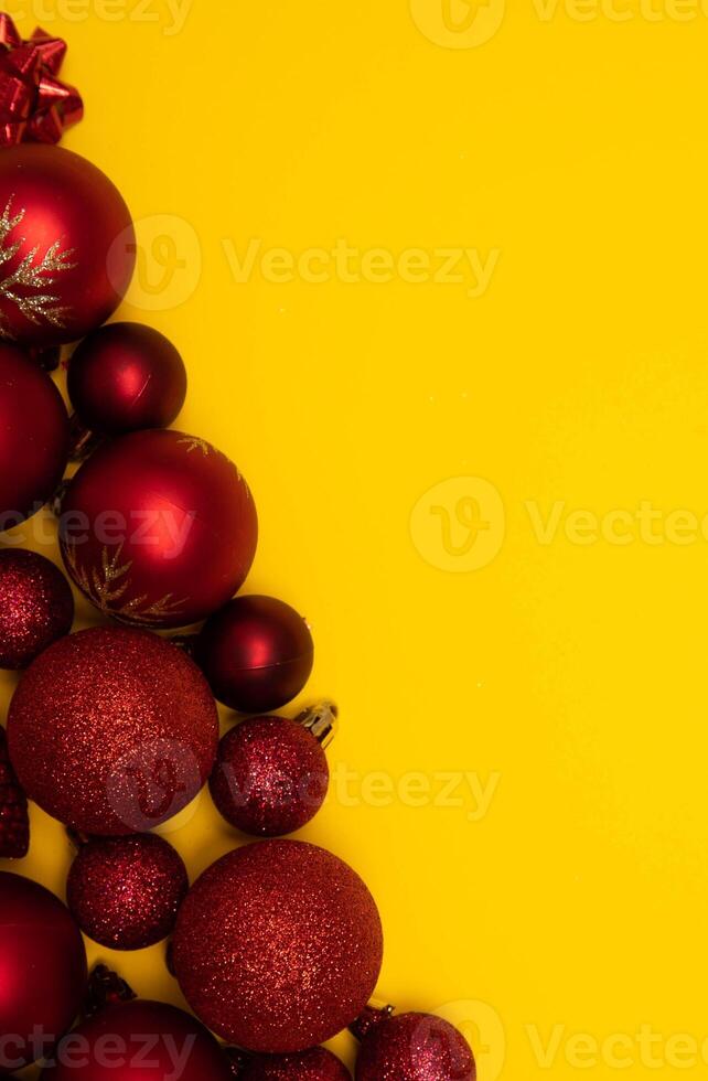 Top view photo tree lined with Christmas tree decorations of red colour on yellow background for greeting card. Xmas backdrop with space for text.Copyspace.Vertical photo.