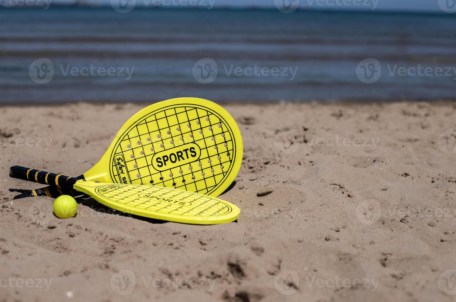 paddle tennis racket and ball of yellow color on tne beach.Copy space.Summer sport background. photo
