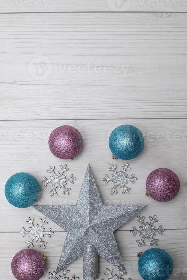Top view photo christmas tree toys of pink and blue colour,silver star decor,wooden silver snowflakes on grey wooden background for greeting card. Xmas backdrop with space for text.Copyspace.Vertical photo.