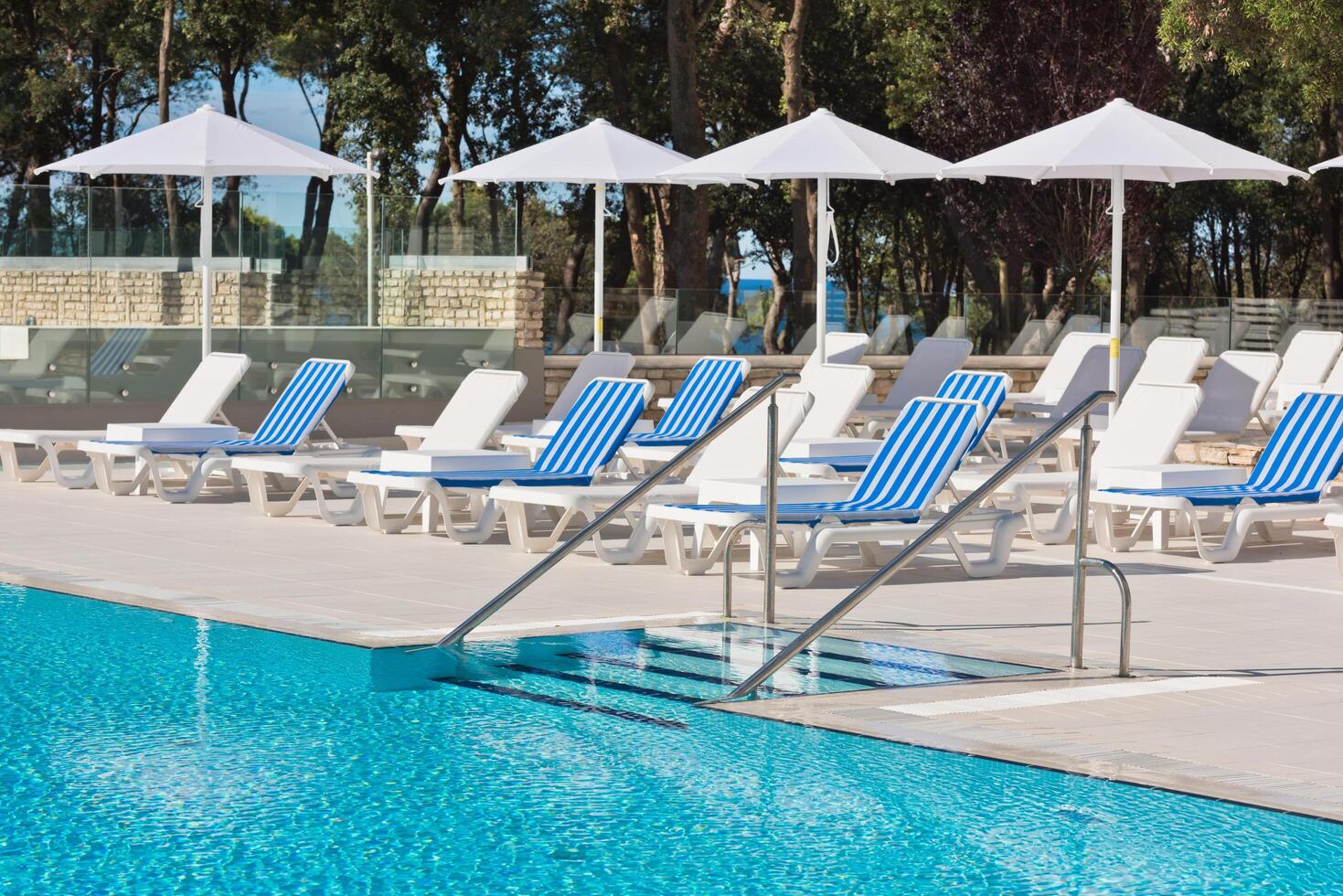 sunbeds and umbrellas by the swimming pool on a sunny day photo