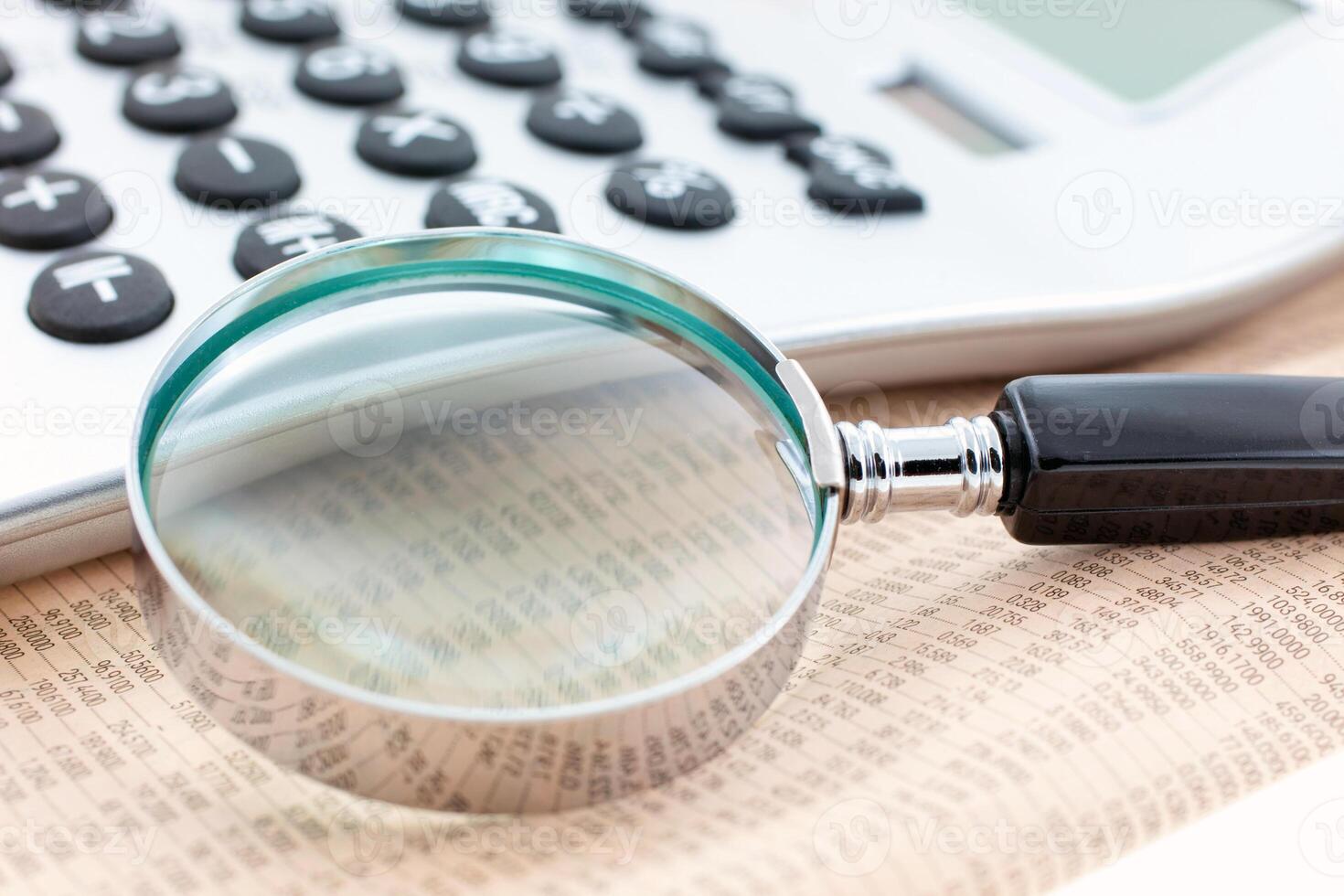 financial newspaper with calculator and magnifier photo