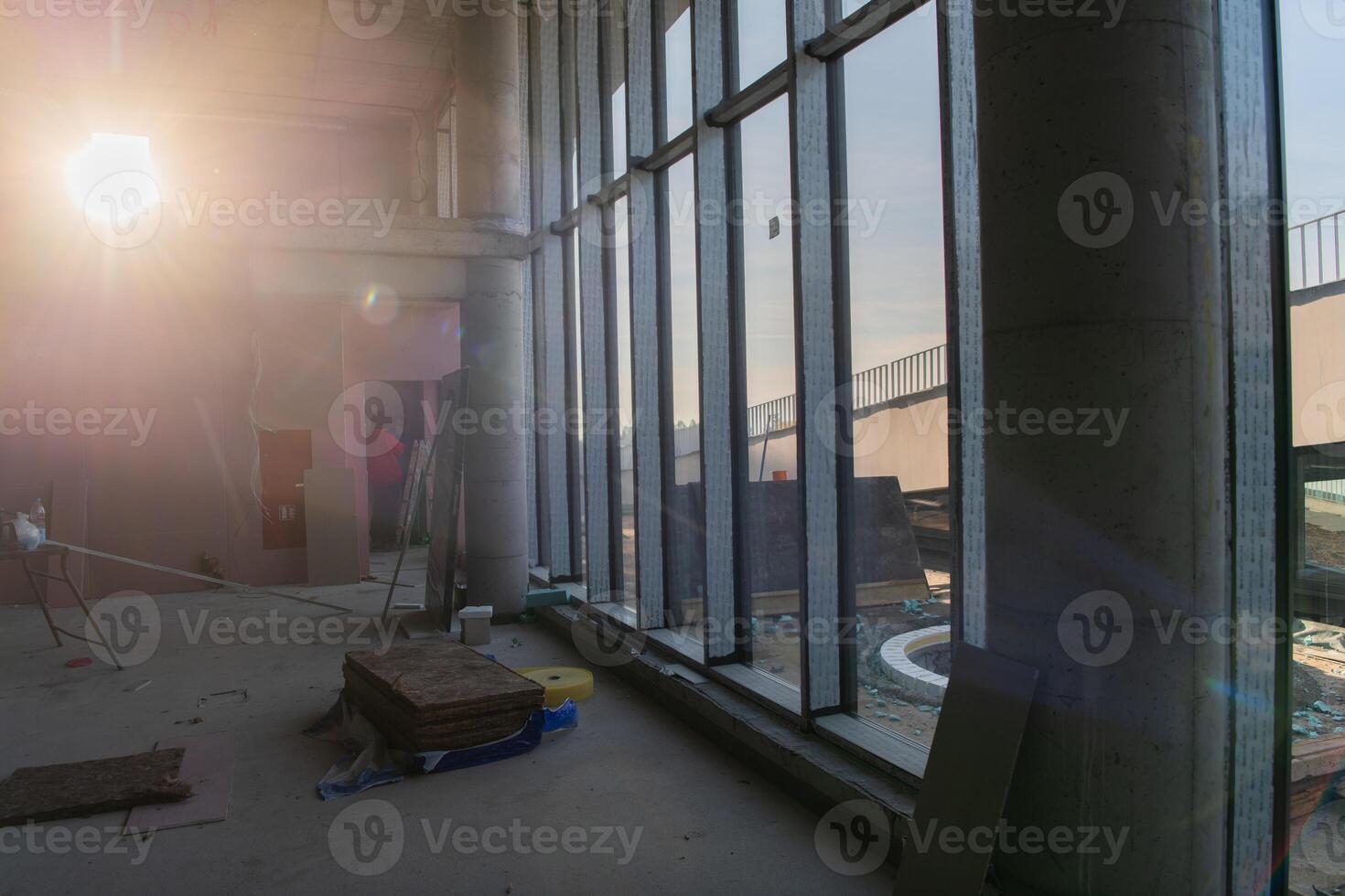 A captivating view of a modern business building under construction, showcasing its raw industrial interior with exposed steel beams and concrete walls bathed in the warm, golden hues of a sunset photo