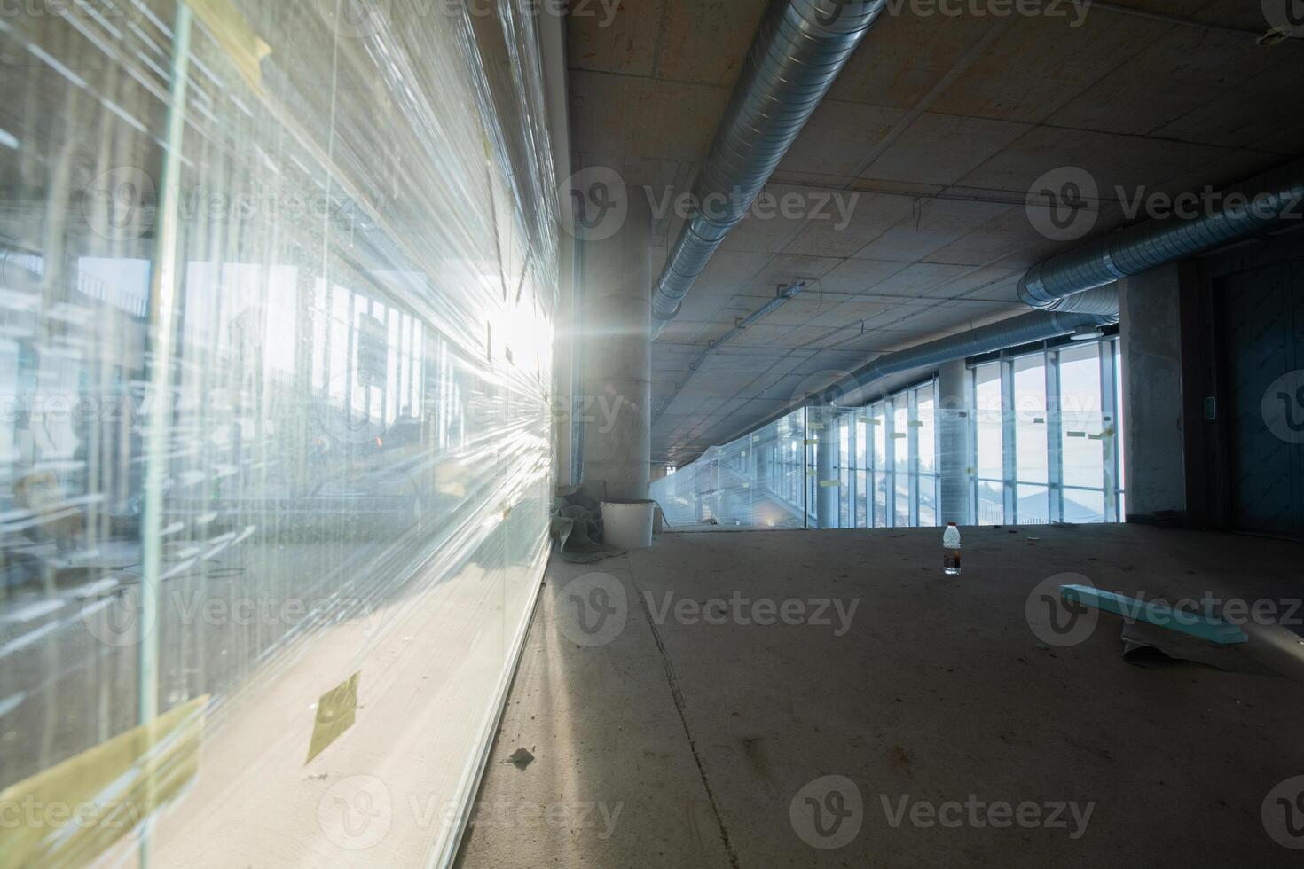 A captivating view of a modern business building under construction, showcasing its raw industrial interior with exposed steel beams and concrete walls bathed in the warm, golden hues of a sunset photo
