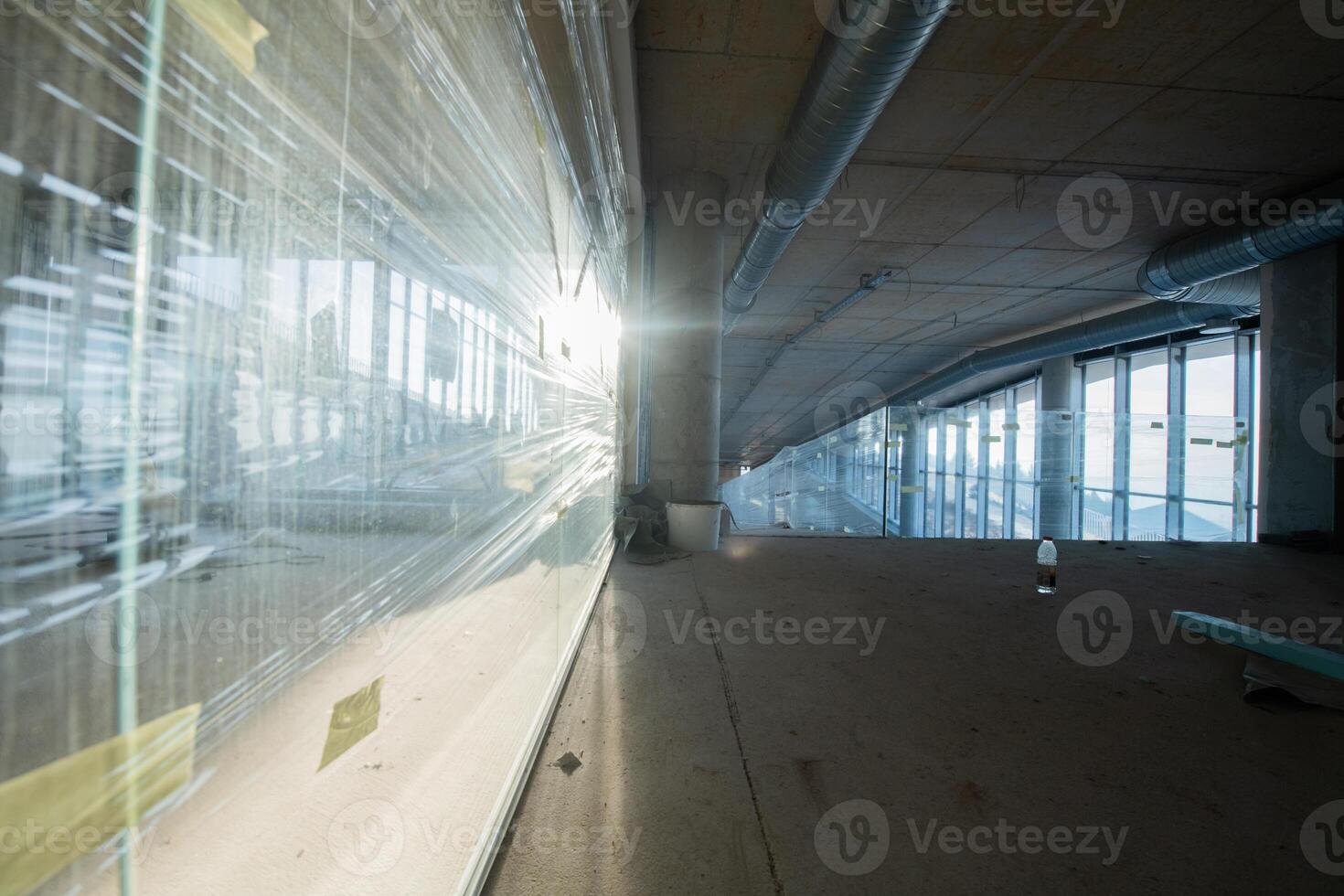 A captivating view of a modern business building under construction, showcasing its raw industrial interior with exposed steel beams and concrete walls bathed in the warm, golden hues of a sunset photo