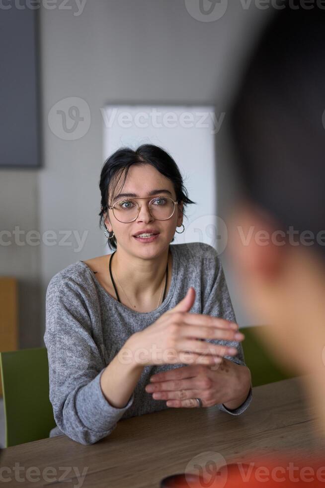A close up portrait of a young businesswoman engaged in a professional meeting, confidently discussing ideas and strategies with her colleagues photo