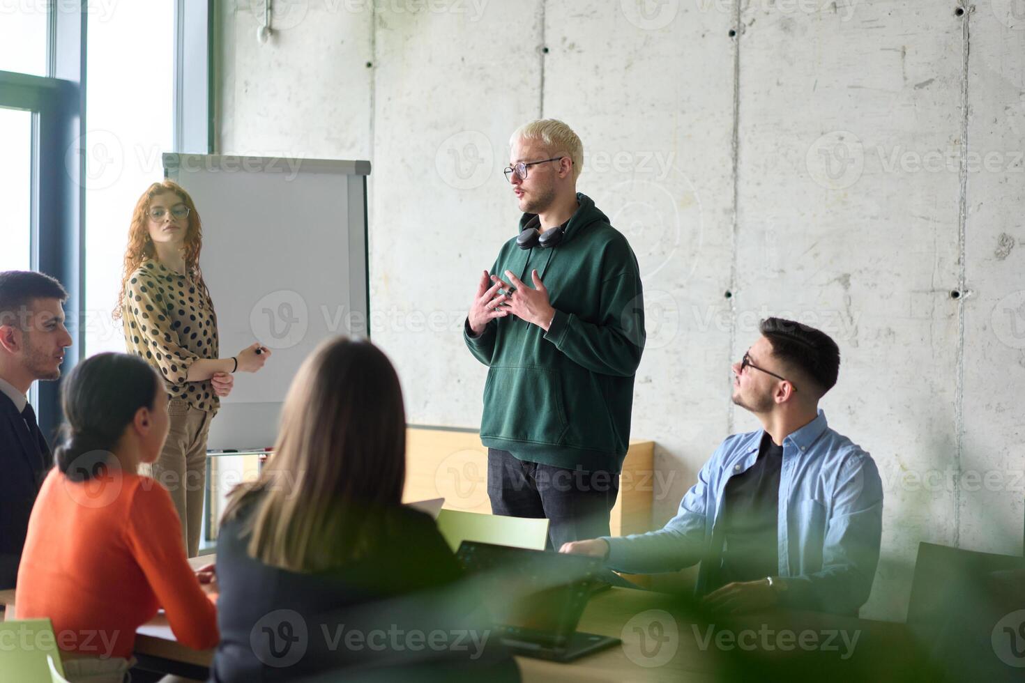 A young, diverse business team sitting together in a modern office, exchanging ideas and business plans, fostering collaboration and innovation for future success. photo
