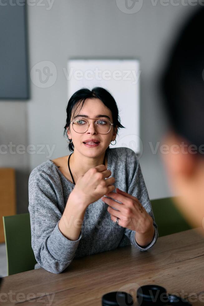A close up portrait of a young businesswoman engaged in a professional meeting, confidently discussing ideas and strategies with her colleagues photo