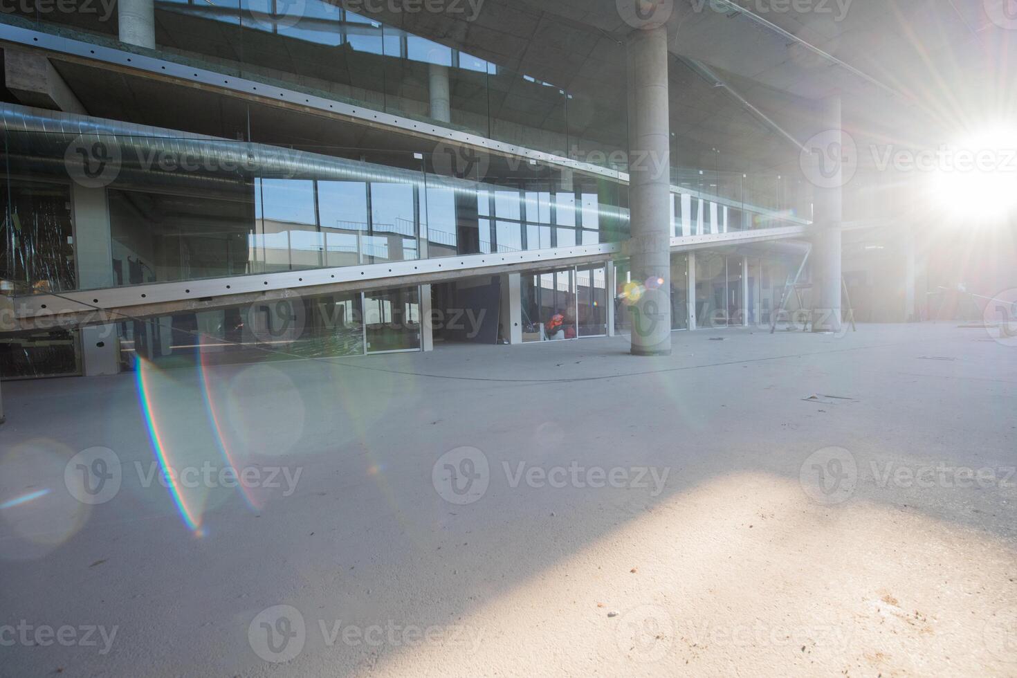 A captivating view of a modern business building under construction, showcasing its raw industrial interior with exposed steel beams and concrete walls bathed in the warm, golden hues of a sunset photo
