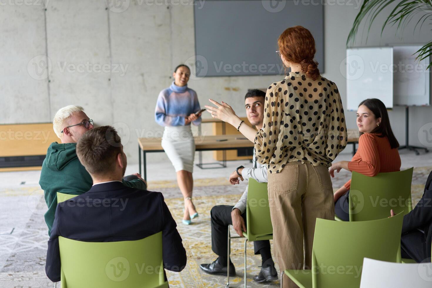 A diverse group of business professionals sits attentively in a modern office, actively participating in a training session led by an instructor, focusing on the latest technological advancements in photo