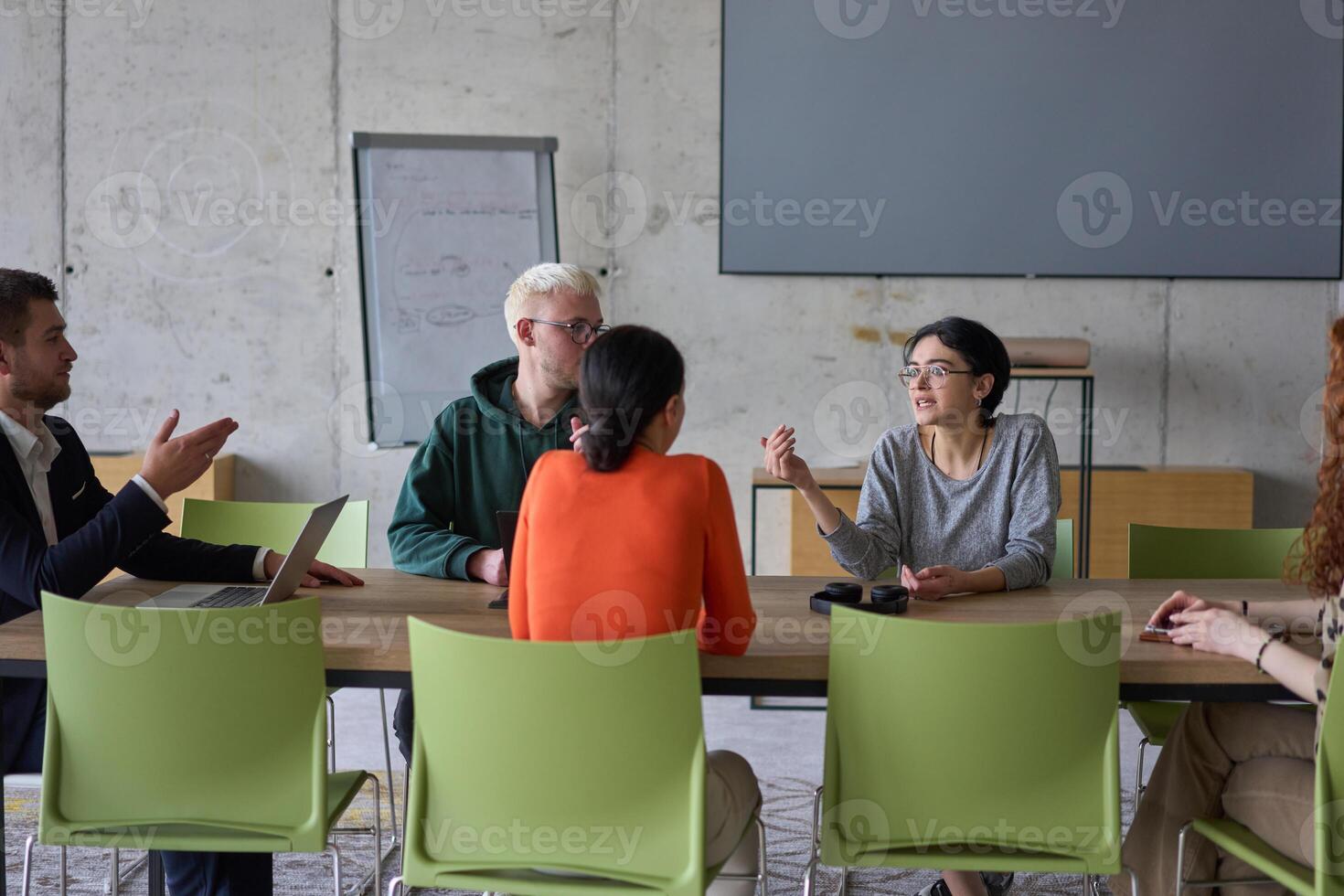 A young, diverse business team sitting together in a modern office, exchanging ideas and business plans, fostering collaboration and innovation for future success. photo