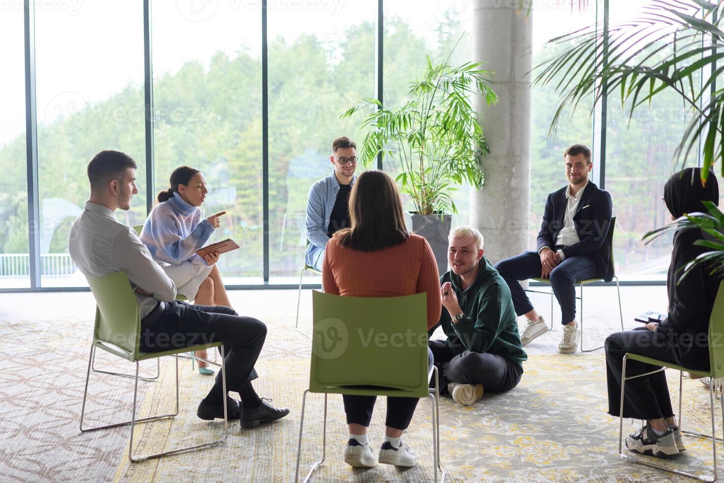 Corporate business team meeting with a manager or coach. Group of happy diverse, multiracial people sitting in a circle photo