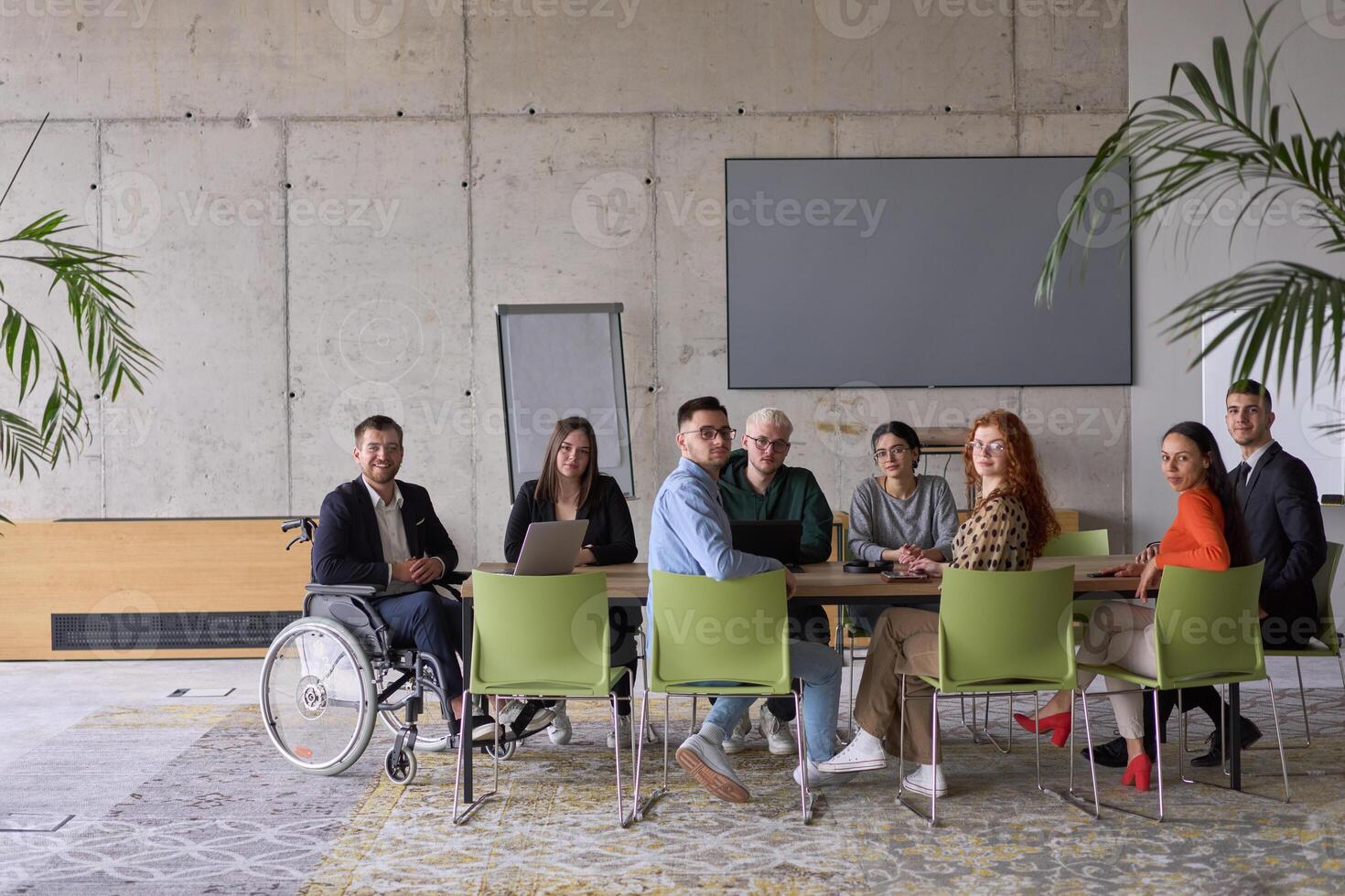 A diverse group of business professionals sitting in an office meeting with their director, who is in a wheelchair, fostering collaboration, leadership, and inclusivity photo