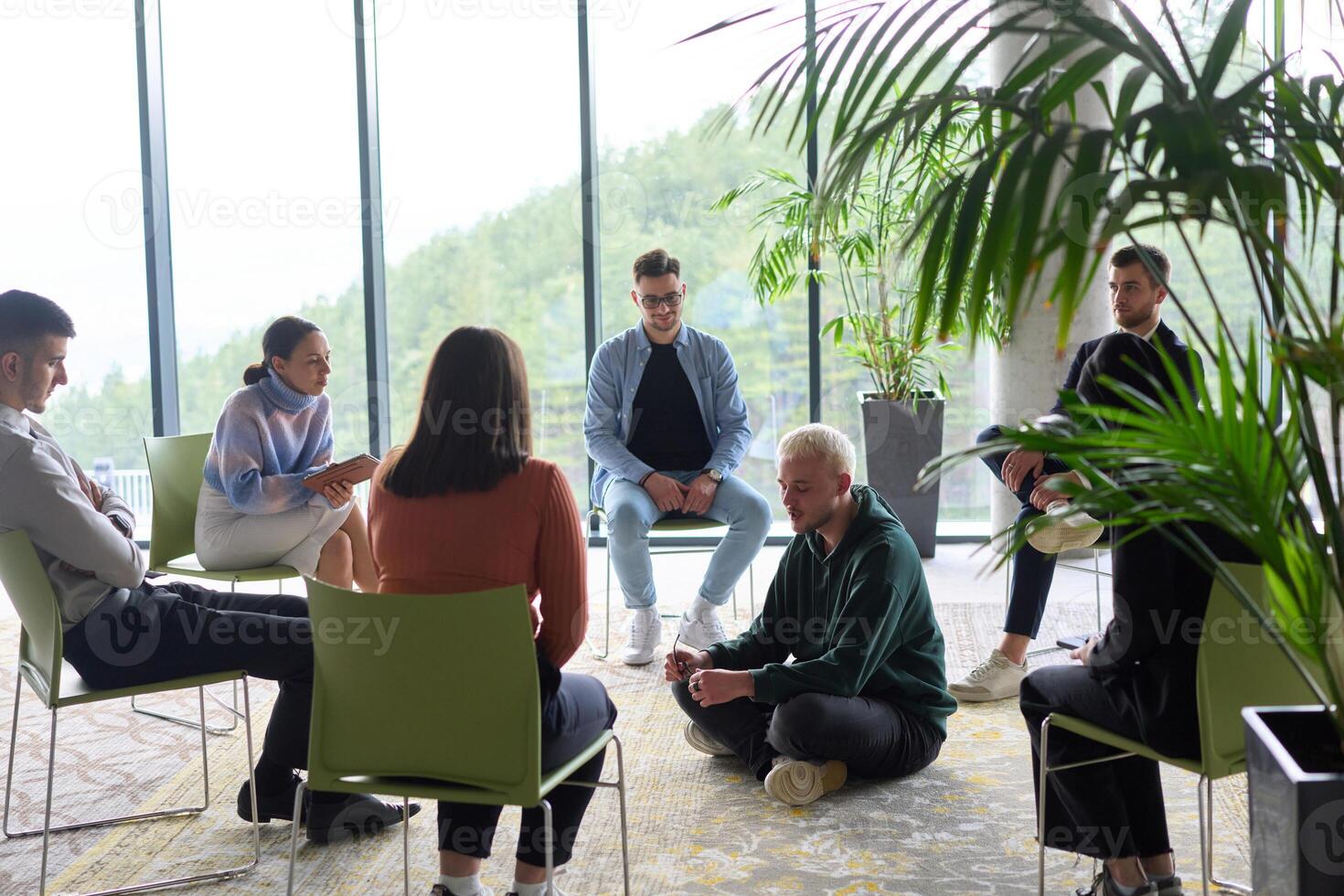 Corporate business team meeting with a manager or coach. Group of happy diverse, multiracial people sitting in a circle photo