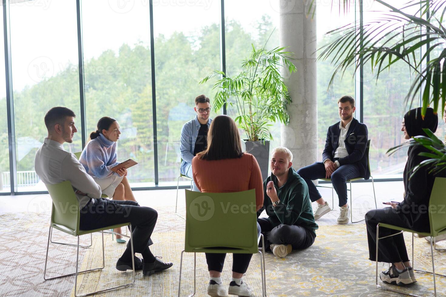 Corporate business team meeting with a manager or coach. Group of happy diverse, multiracial people sitting in a circle photo