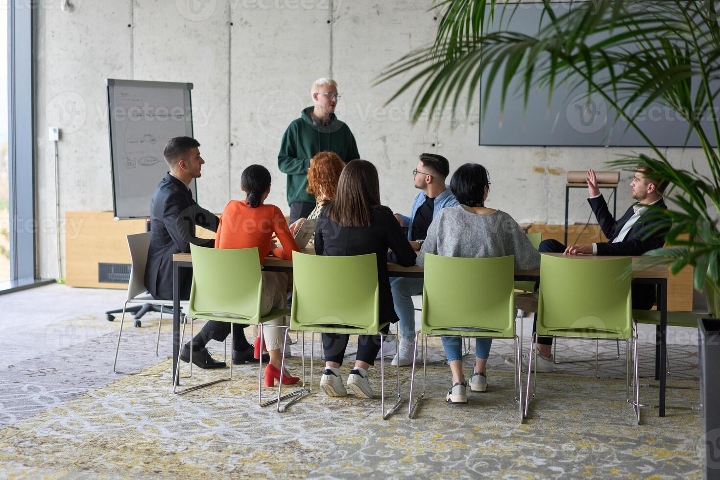 A young, diverse business team sitting together in a modern office, exchanging ideas and business plans, fostering collaboration and innovation for future success. photo