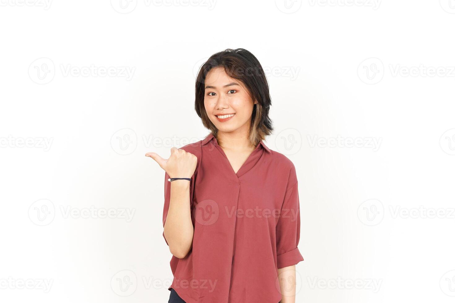 Showing and Pointing Product With Thumb Of Beautiful Asian Woman Isolated On White Background photo