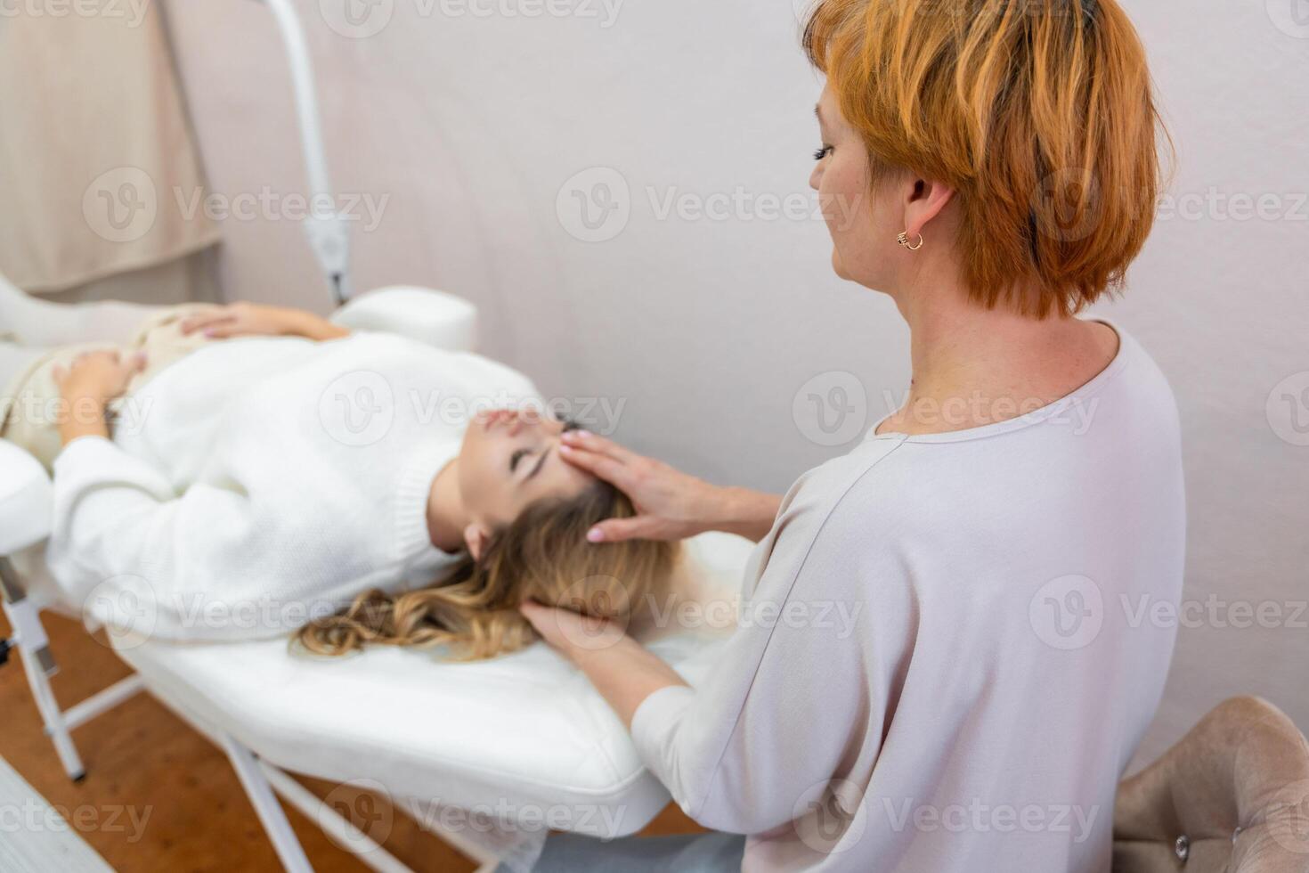 Healer woman performing set of 32 points of access bars on young woman head, stimulating positive change thoughts and emotions in salon. Alternative medicine concept. High quality photo
