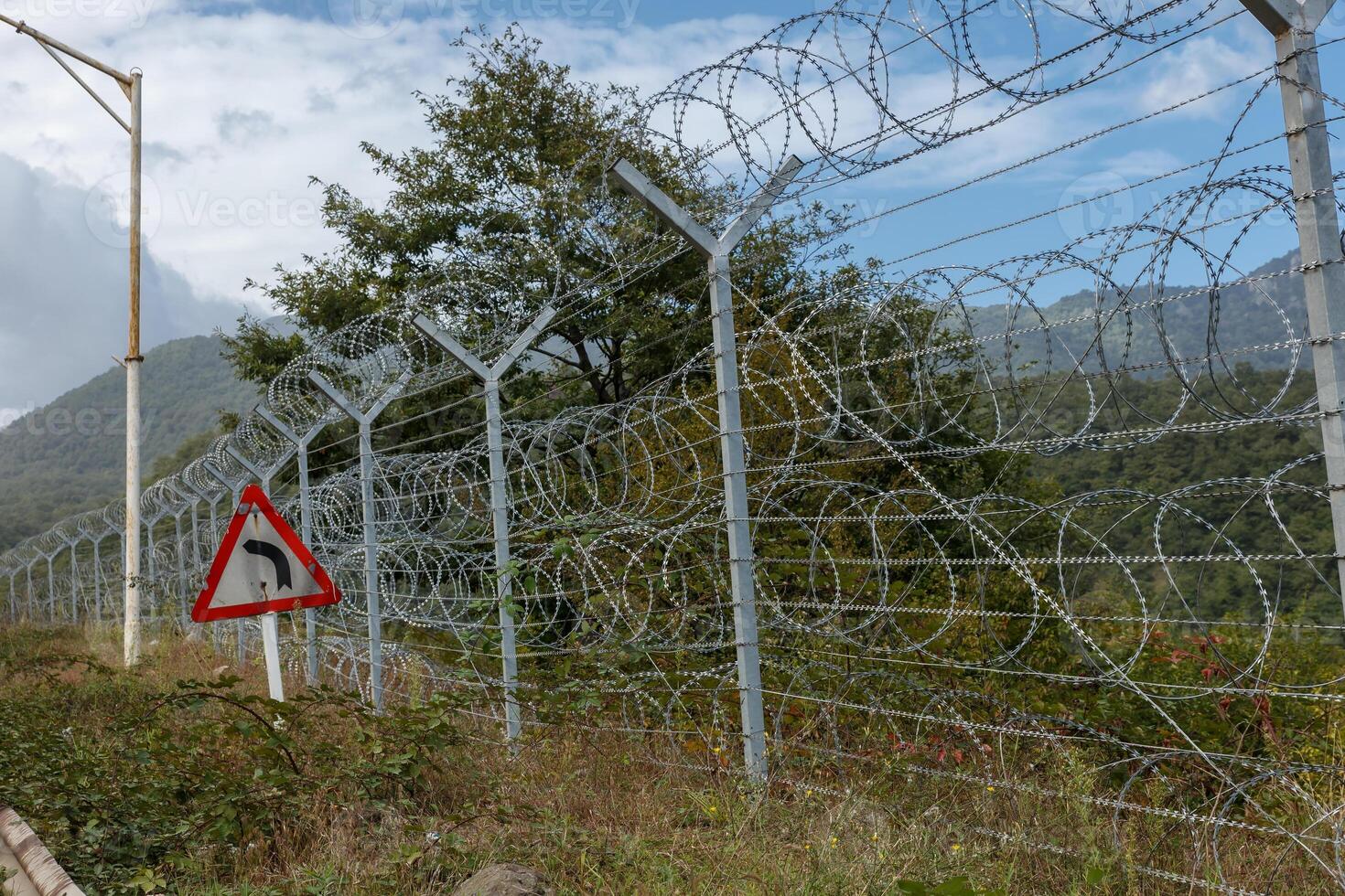 Border between Iran and Azerbaijan with barbed wire fence and mountainous backdrop photo