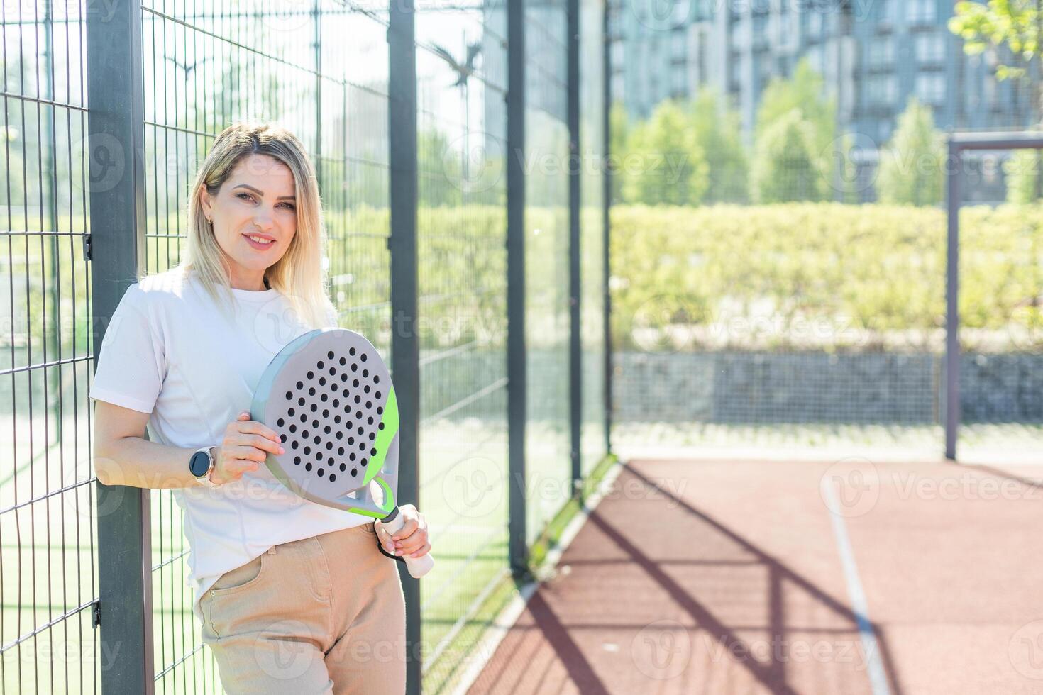 Sportive young girl with racquet playing padel in court. photo