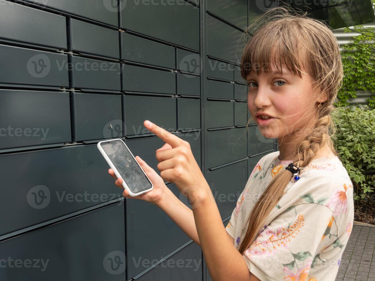 teenage girl opens mail delivery from smartphone. Post terminal machine and parcel delivery. photo