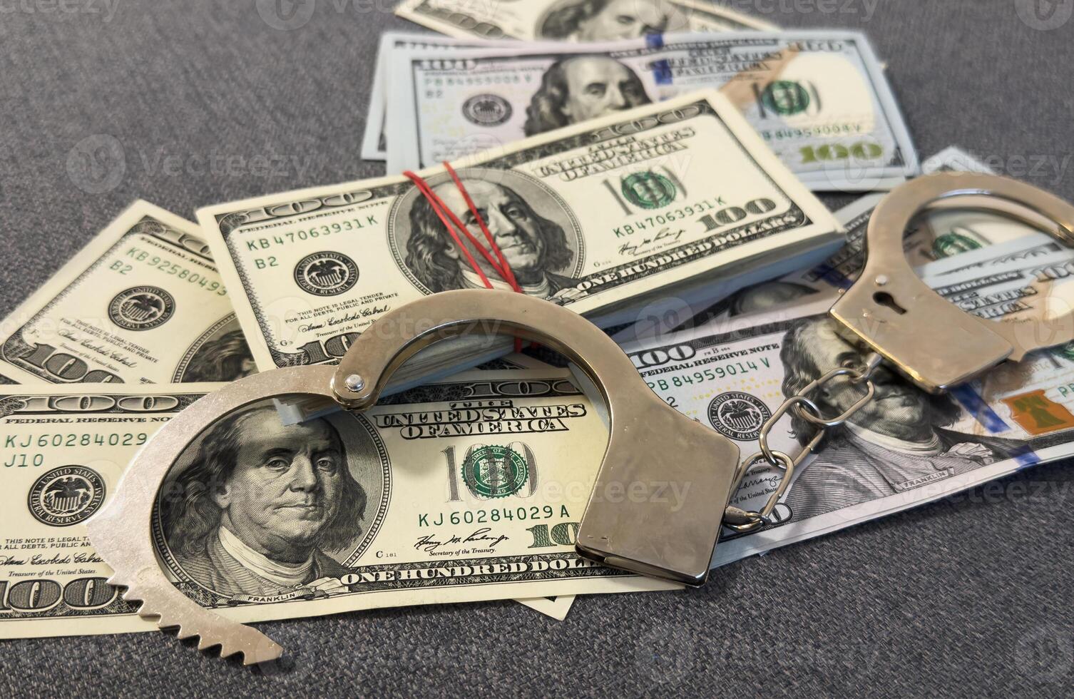 Financial crime, fraud, money laundering, corruption, or law enforcement . Bundles of US dollar 100 bills in a small case, alongside a pair of handcuffs placed over the US dollar currency. photo