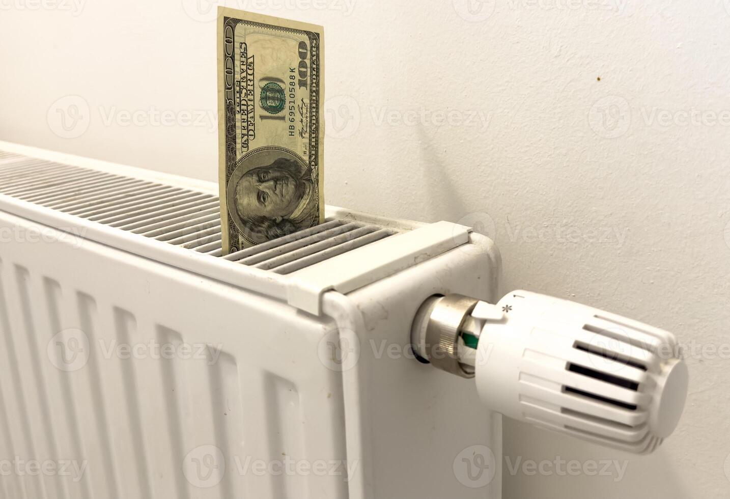 A heating radiator battery from which bills stick out. The concept of high heating expenses. Rise in energy prices, energy crisis and recession photo