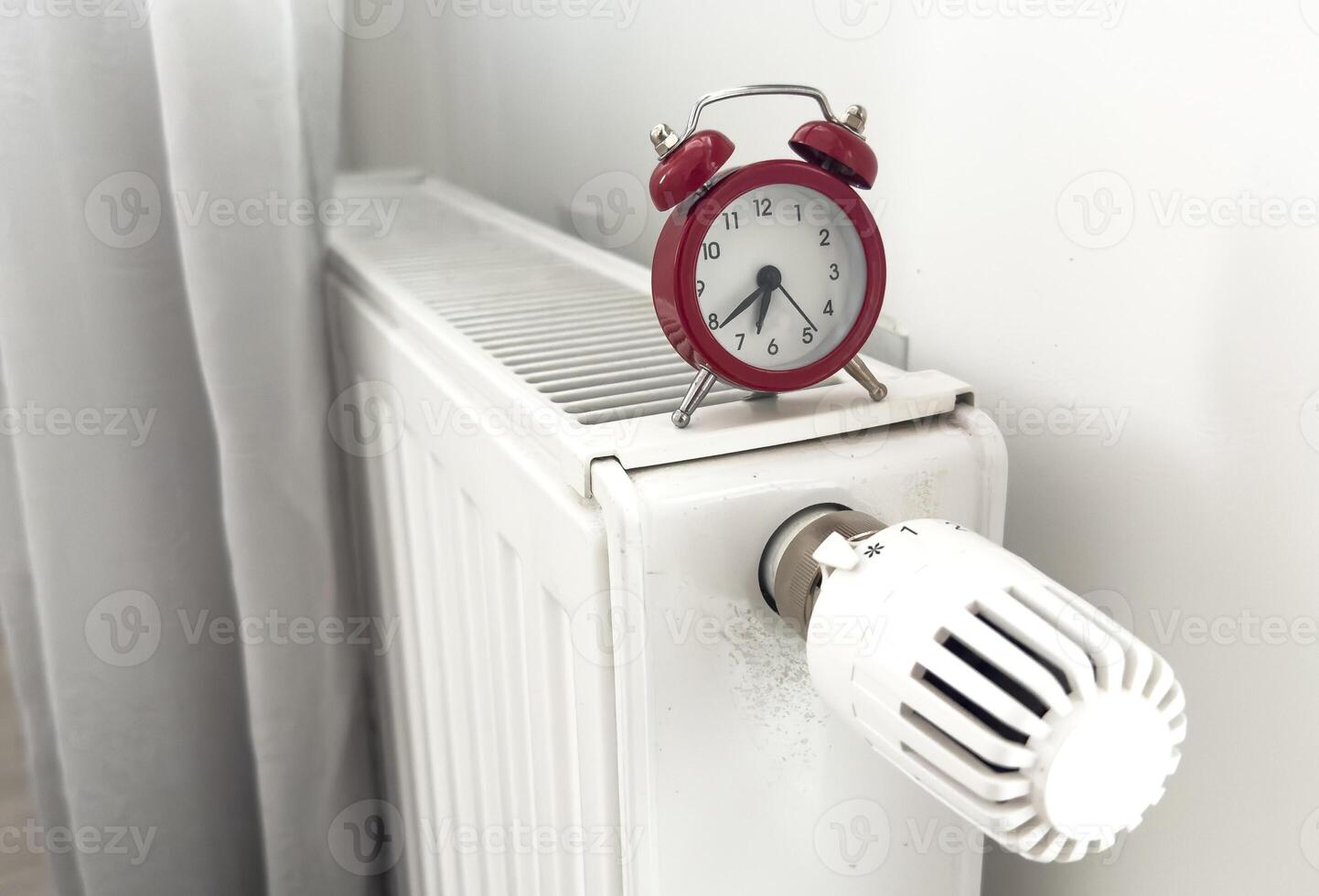 alarm clock on heating radiator against light background. Space for text. photo