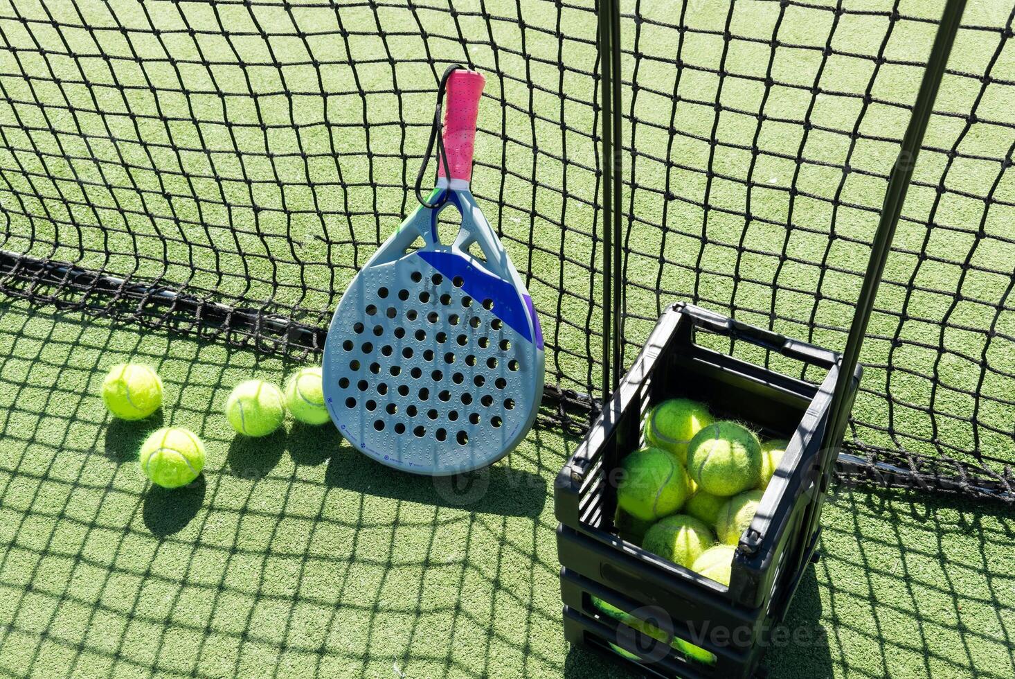 Paddle racket with a ball ready to play the fastest growing sport in recent years worldwide. Padel court in summer, the perfect time to practice this sporting discipline and release stress. photo
