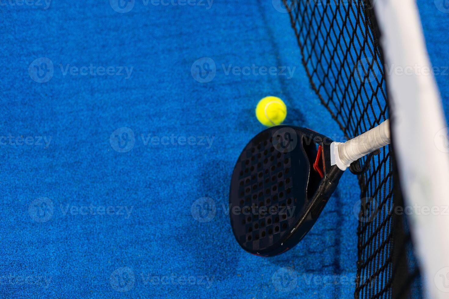 Black professional paddle tennis racket and ball with natural lighting on blue background. Horizontal sport theme poster, greeting cards, headers, website and app photo