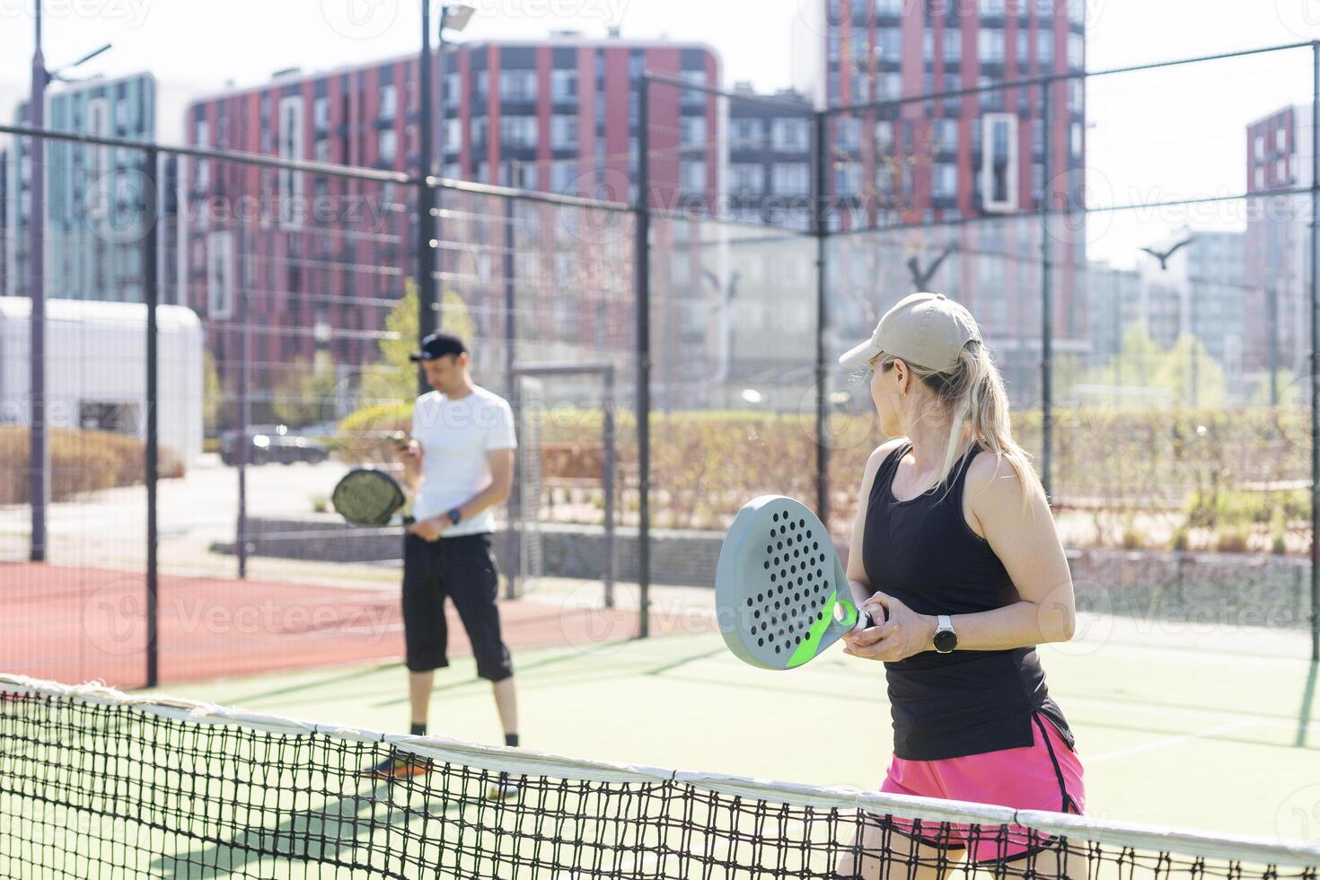 hands of a woman paddle player is holding balls and the racket at the background at the beginning of the match outdoors photo