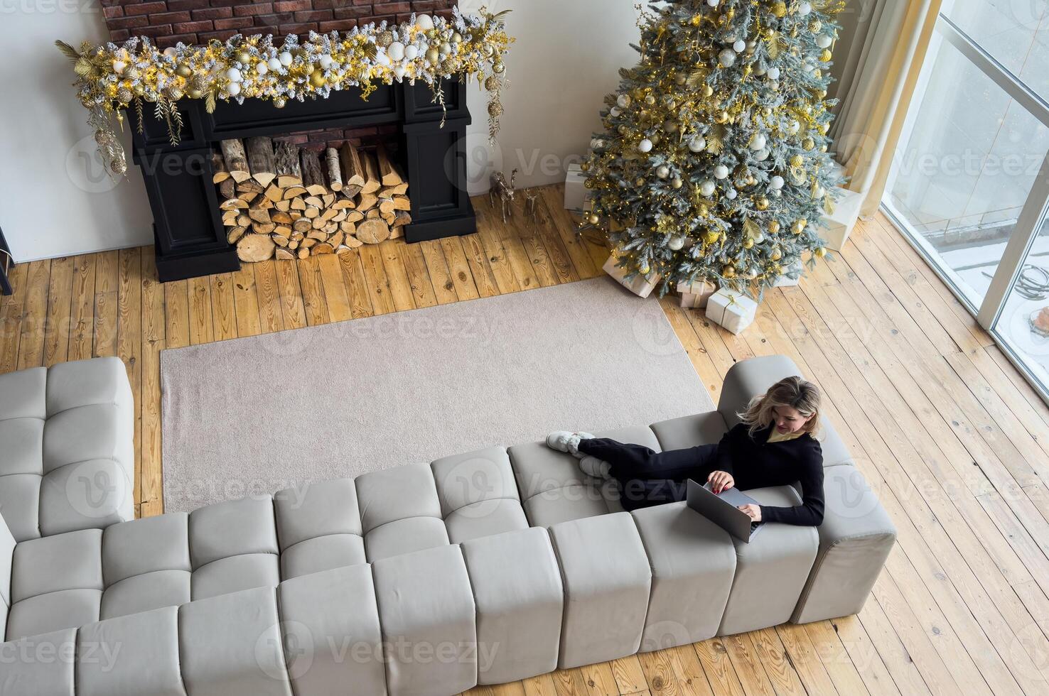 Happy female professional in talking to client over call while staying at home on Christmas. Cheerful business manager explaining new details of project on background of Christmas tree photo