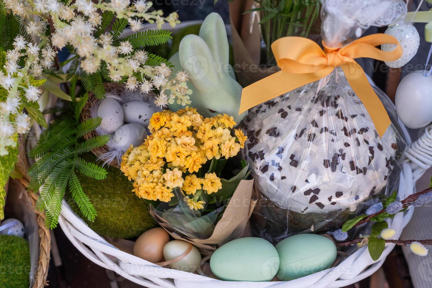 Easter basket with eggs decorated with wreath made of carnations, buxus and catkins. photo