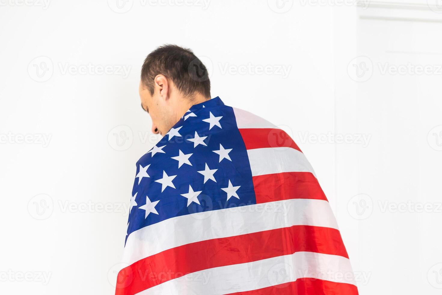 Beautiful young man holding an American flag on grey background photo